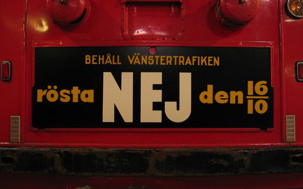 En skylt på baksidan av en röd buss med texten Behåll vänstertrafiken, rösta nej den 16/10